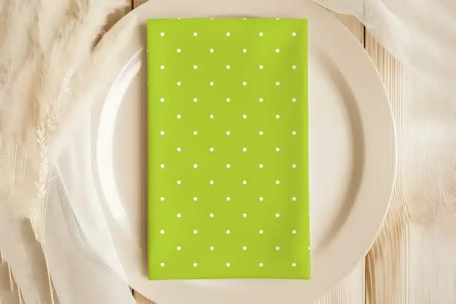 Lime Green Napkin With White Polka Dots On A Beige Plate.