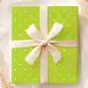 A Lime Green Gift Box With White Polka Dots And A Beige Ribbon.