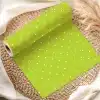 A Roll Of Lime Green Wrapping Paper With White Polka Dots Sits On A Woven Placemat.