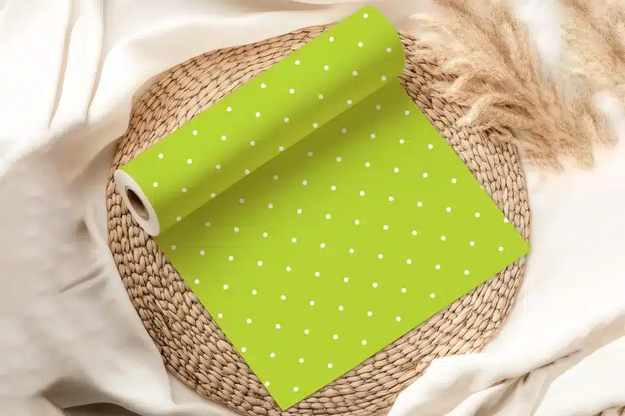 A Roll Of Lime Green Wrapping Paper With White Polka Dots Sits On A Woven Placemat.