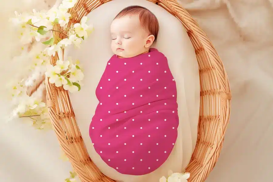 Sleeping baby swaddled in a pink polka dot wrap.