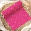 Pink Wrapping Paper Roll With White Polka Dots, Partially Unrolled On A Woven Placemat.