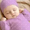 Sleeping Baby Wearing A Lavender Polka Dot Onesie And Matching Hat.
