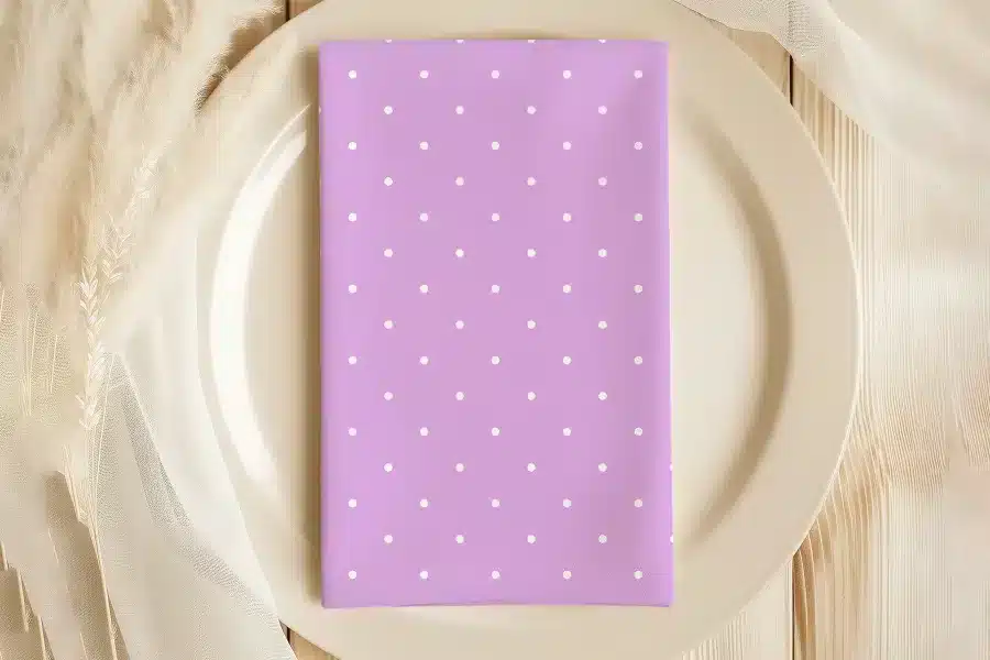 Lavender Napkin With White Polka Dots On A Beige Plate.