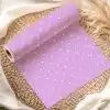A Roll Of Lavender Wrapping Paper With White Polka Dots Rests On A Woven Placemat.
