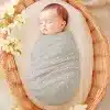 Sleeping Baby Swaddled In A Gray Polka Dot Blanket Inside A Wicker Basket.