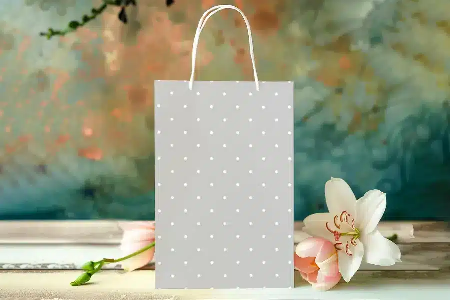 Grey Polka Dot Gift Bag With Pink Flowers In The Foreground.