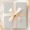 A Gray Gift Box With White Polka Dots And A Beige Ribbon.