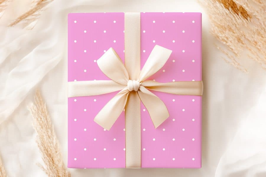 Pink Gift Box With White Polka Dots And A Beige Ribbon Tied In A Bow.