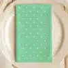 Mint Green Napkin With White Polka Dots On A Beige Plate.