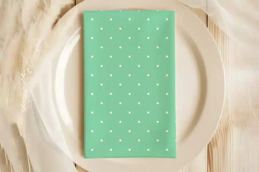 Mint Green Napkin With White Polka Dots On A Beige Plate.