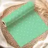 A Roll Of Light Green Wrapping Paper With White Polka Dots Is Partially Unrolled On A Woven Placemat.