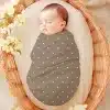 Sleeping Baby Swaddled In A Taupe Polka Dot Blanket Inside A Wicker Basket.