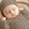 Sleeping Baby Wearing A Taupe Polka Dot Onesie And Matching Hat.