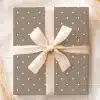 A Taupe Gift Box With White Polka Dots And A Beige Ribbon Tied In A Bow.