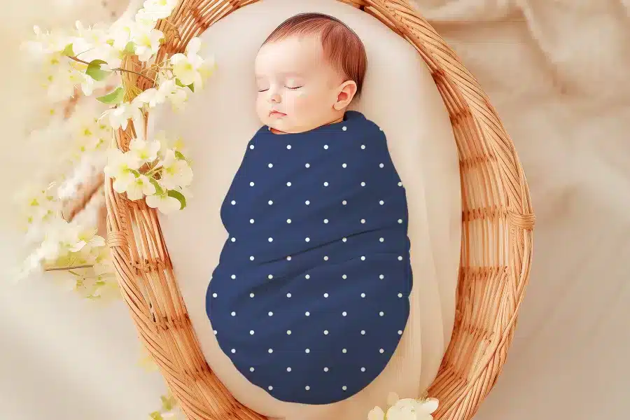 Sleeping baby swaddled in a navy blue polka dot blanket.