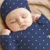 Sleeping Baby Wearing A Navy Blue Polka Dot Hat And Outfit.