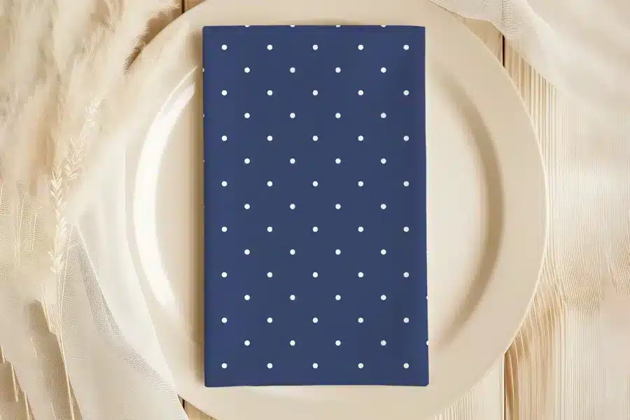 Navy Blue Napkin With White Polka Dots On A Beige Plate.