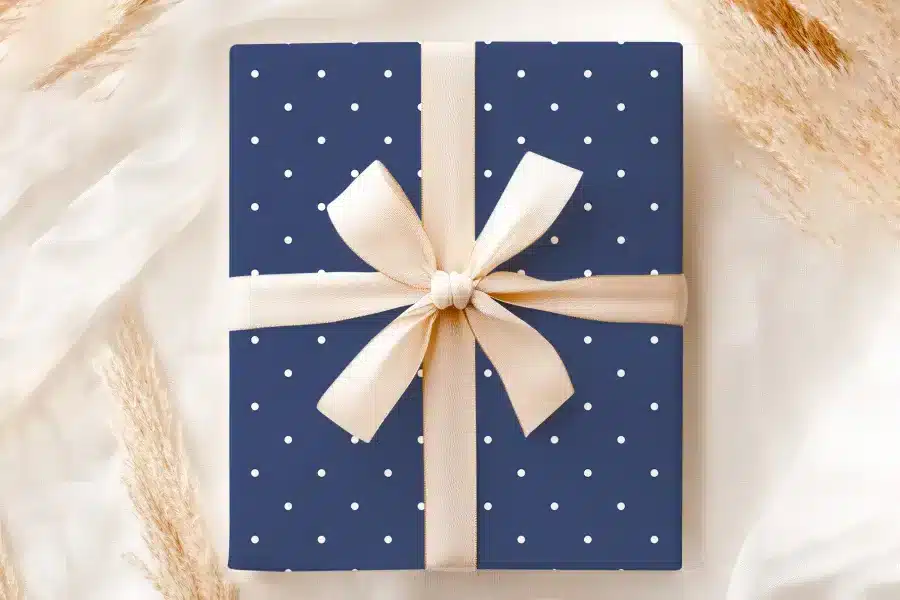 Navy Blue Gift Box With White Polka Dots And A Beige Ribbon.