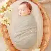 Sleeping Baby Swaddled In A Light Beige Polka Dot Blanket Inside A Wicker Basket.