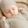 A Baby Sleeping Peacefully, Wearing A Taupe Polka Dot Onesie And Matching Hat.