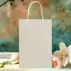Beige Gift Bag With White Polka Dots, Next To Pink Tulips And A White Lily.