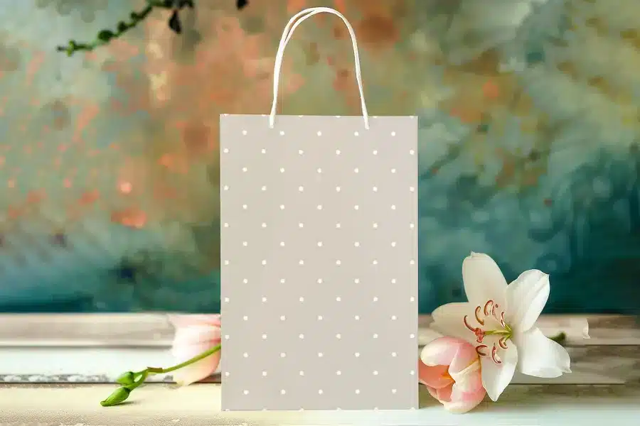 Beige Gift Bag With White Polka Dots, Next To Pink Tulips And A White Lily.