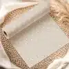 A Roll Of Beige Wrapping Paper With White Polka Dots, Partially Unrolled On A Woven Placemat.