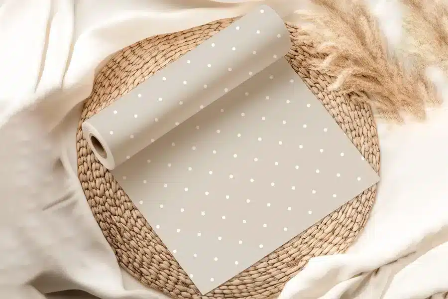A Roll Of Beige Wrapping Paper With White Polka Dots, Partially Unrolled On A Woven Placemat.