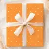 An Orange Gift Box With White Polka Dots And A Cream-Colored Ribbon.