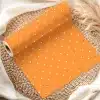 Orange Wrapping Paper With White Polka Dots, Partially Unrolled On A Woven Mat.