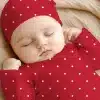 Sleeping Baby Wearing A Red Polka Dot Onesie And Matching Hat.