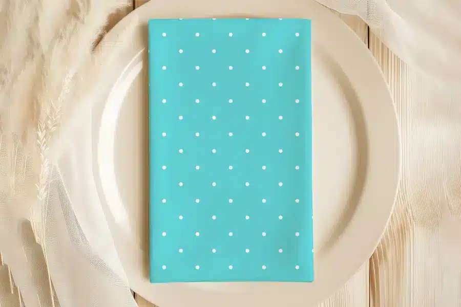 Teal Napkin With White Polka Dots On A Beige Plate.