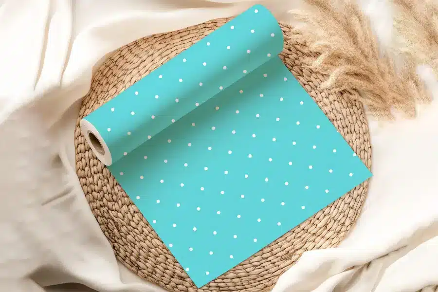 A Roll Of Light Teal Wrapping Paper With White Polka Dots.