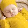 Sleeping Baby Wearing A Yellow Polka Dot Onesie And Matching Hat.