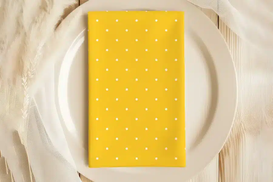 Yellow Napkin With White Polka Dots On A Beige Plate.