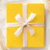 A Yellow Gift Box With White Polka Dots And A Beige Ribbon.