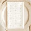 White Napkin With Gold Polka Dots On A Beige Plate.