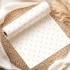 White Wrapping Paper With Gold Polka Dots Rolled On A Woven Placemat.