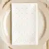 White Napkin With Light Gray Polka Dots On A Beige Plate.