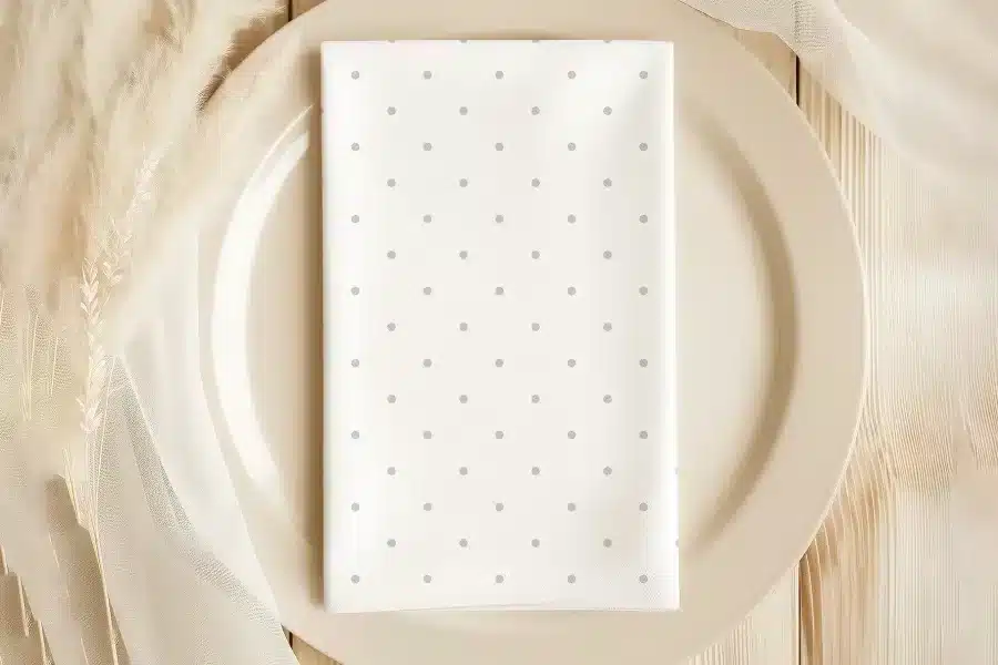 White Napkin With Light Gray Polka Dots On A Beige Plate.