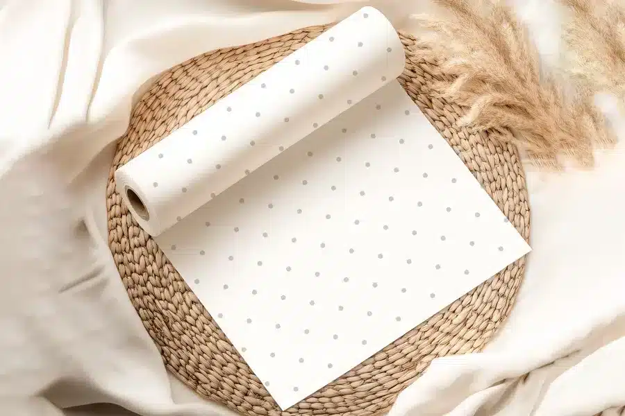 A Roll Of White Paper With Small Gray Dots, Partially Unrolled On A Woven Placemat.