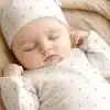Sleeping Baby Wearing A Pink Polka Dot Onesie And Matching Hat.
