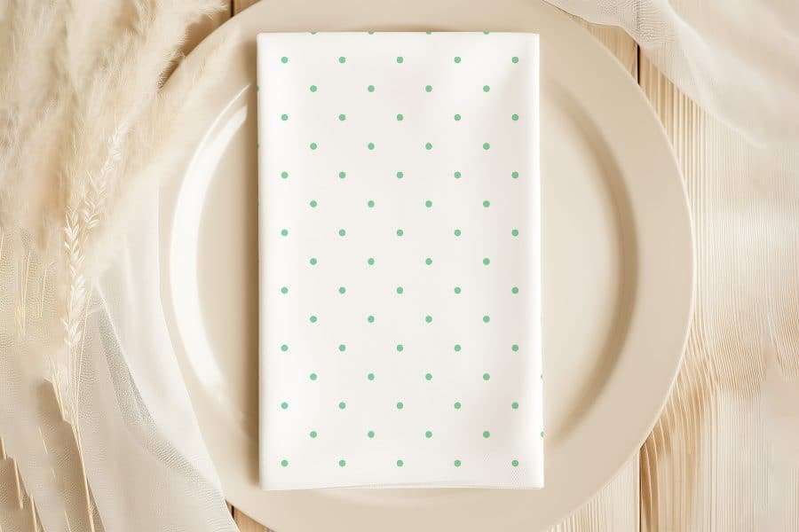White Napkin With Light Green Polka Dots On A Beige Plate.