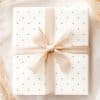 A Gift, Wrapped In White Paper With Light Green Polka Dots And Tied With A Beige Ribbon.