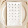 A White Napkin With Navy Blue Polka Dots Sits Folded On A Beige Plate.