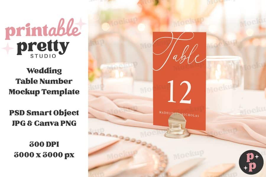 An Orange Wedding Table Number Card, Displaying The Number 12 And Names Madeline And Nicholas, Stands In A Gold Holder On A Table.