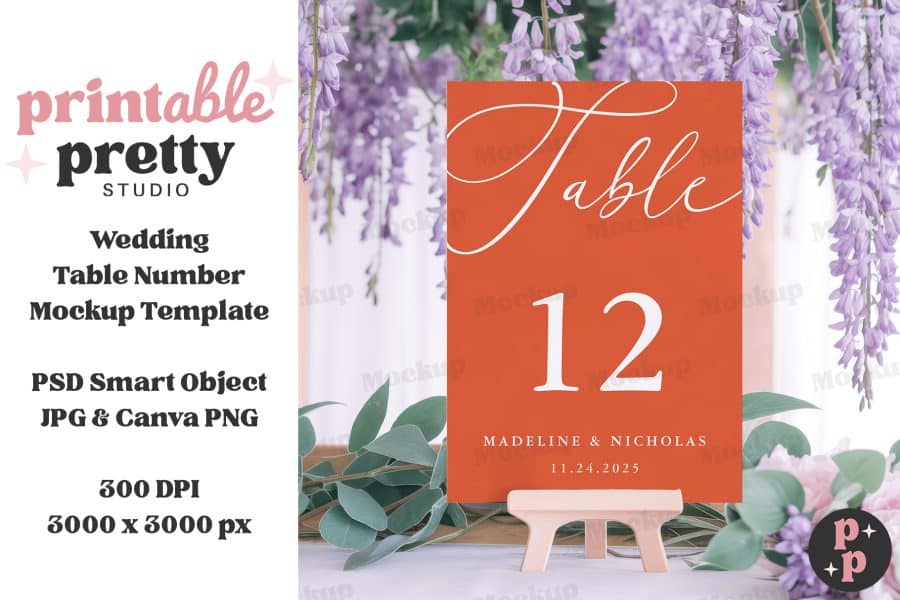 A Terracotta-Colored Wedding Table Number Card, Displaying &Quot;Table 12&Quot; And The Names Madeline &Amp; Nicholas With The Date, Sits On A Small Wooden Easel.