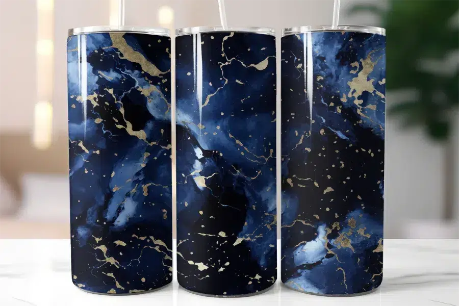 Three Navy Blue And Gold Marble-Patterned Tumblers With Straws.