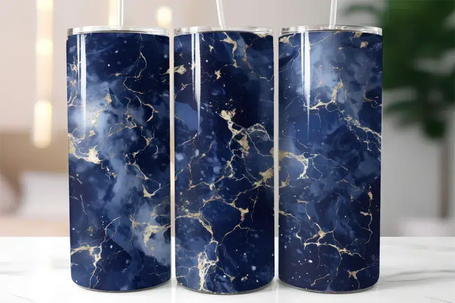 Three Navy Blue And Gold Marble Patterned Tumblers With Straws.